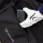 A close-up of a black Arccos golf bag showing a zippered pocket with a white golf glove holding the Arccos Air charger