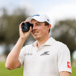Golfer holding a rangefinder on a golf course