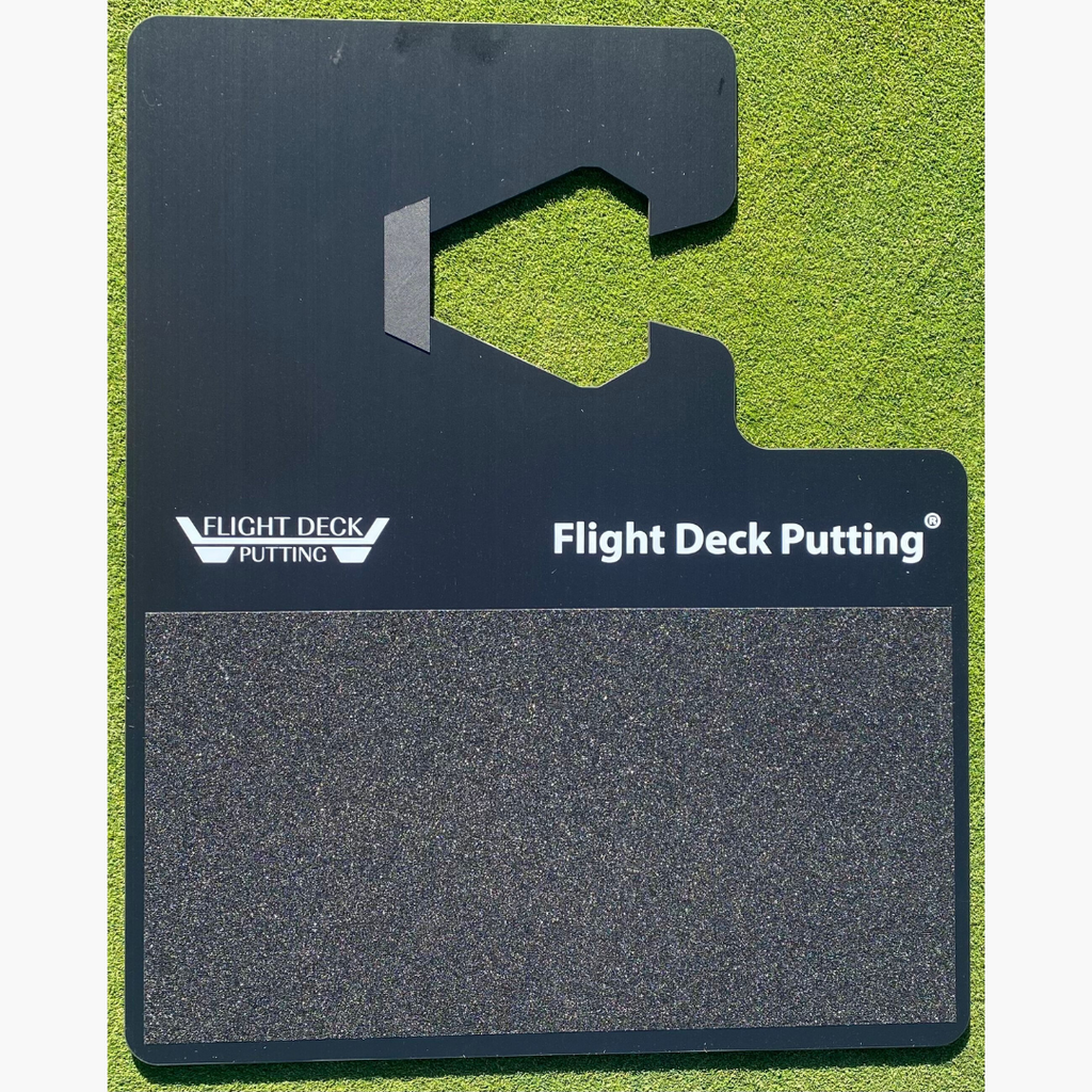 A black indoor putting adapter with the Flight Deck Putting brand logo, designed to be placed on a golf mat for training.