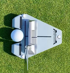 Overhead view of a mallet putter squared up to the ball gate of the Flight Deck Putting Tour trainer on a putting green, showing face-to-line alignment