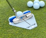 Putter squared up to the ball in the Flight Deck Putting Tour Soft guide on a practice green, with a cluster of practice balls visible in the background