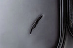 Macro close-up of the embossed Fourteen Golf feather logo badge on the matte black caddie bag body panel beside the zipper