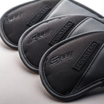 Close-up of three Fourteen Golf black iron head covers fanned out, showing embossed club number markings and FOURTEEN rubber badge on textured nylon and PU leather construction