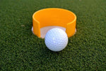 Golf ball rolling toward the EyeLine Golf Bullseye Cup yellow target reducer fitted inside a putting green hole