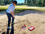 Golfer setting up address position over the EyeLine Golf Bunker Pro System board and entry peg in a course bunker, fairway and green visible in background