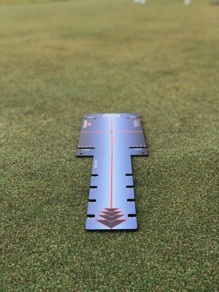 Overhead view of the EyeLine Bender Putting Board laid flat on the green showing red target line and path slots