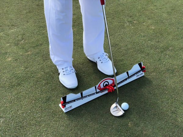 Golfer at address with putter and ball at the EyeLine Golf Edge Putting Rail with Memory Band, showing proper foot position on either side of the rail
