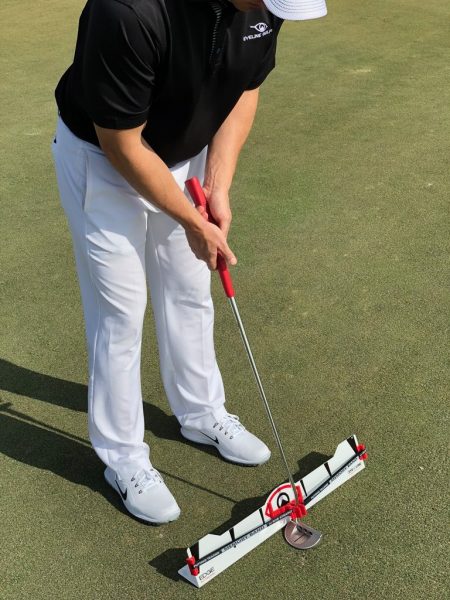 EyeLine Golf-branded golfer putting over the Edge Putting Rail with Memory Band system, demonstrating full setup and stroke position on the practice green