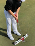 EyeLine Golf-branded golfer putting over the Edge Putting Rail with Memory Band system, demonstrating full setup and stroke position on the practice green