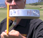 EyeLine Golf-branded instructor holding up a putter with the yellow EyeLine Golf Putter Guide attached to the face, demonstrating correct fit and positioning
