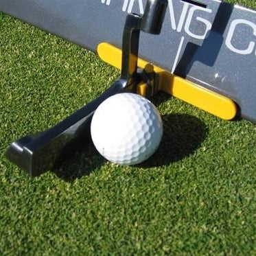 A golf putter guide attached to a mallet, with a white golf ball in the center and a green background.