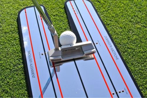 Front-on close-up of putter face and golf ball centred on the EyeLine Golf Classic Putting Mirror, with shoulder alignment labels and red lines visible on both sides of the U-channel