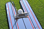 Low-angle view of putter and ball on the EyeLine Golf Classic Putting Mirror showing the full width of the shoulder alignment zones and red stripe lines stretching away from the putter gate