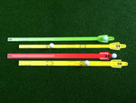 Four EyeLine Golf Putting Sword rails laid out on the green in green, yellow, red, and yellow colour variants, each with a golf ball seated in the ball channel