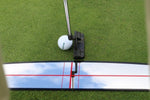 Close-up of putter face and golf ball at the EyeLine Golf Shoulder Mirror edge, showing the red crosshair alignment lines reflected in the mirror surface