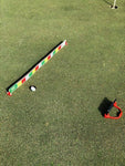 EyeLine Golf SloMo Screen laid on the green beside a golf ball and Thumbs-Up smartphone holder, set up for slow-motion putt roll analysis toward the hole