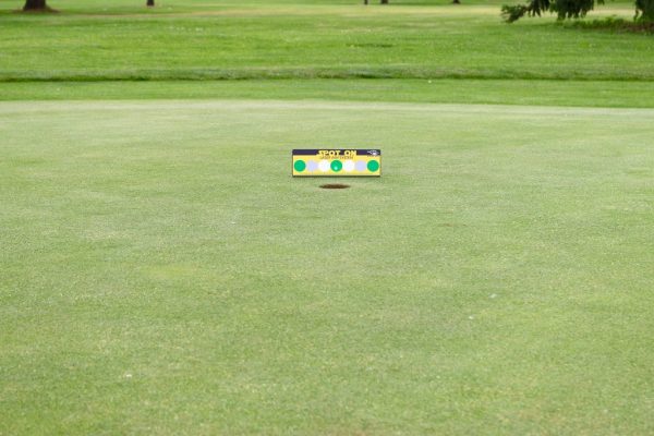 Wide view of the EyeLine Golf Spot On Laser target positioned near the cup on the green, showing the full putting surface and surrounding course context