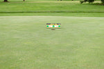 Wide view of the EyeLine Golf Spot On Laser target positioned near the cup on the green, showing the full putting surface and surrounding course context