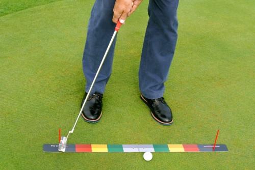 Golfer bent over in putting stance with the EyeLine Golf Stroke Meter stretching away in front, red and yellow stroke zones framing the putter and ball from a straight-on perspective