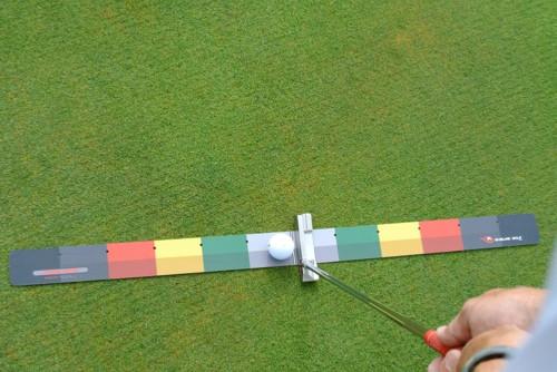 Bird's-eye view of the EyeLine Golf Stroke Meter with putter and ball centred at impact, showing the full symmetrical colour-coded mat from above