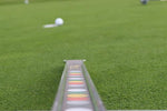 Ground-level view along the EyeLine Golf Sweet Roll Rail with colour-coded impact zones in the foreground and a rolling golf ball on the green in the background
