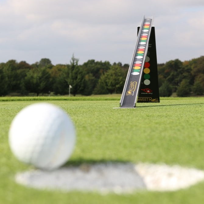 Golf ball rolling toward the EyeLine Golf Sweet Roll Rail System on the green, with the colour-coded ramp visible in the background for putt quality feedback