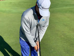 Eyeline Golf-branded instructor demonstrating proper putting posture and grip using the Putting Pendulum Rod on the green