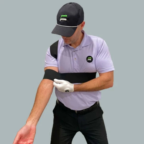 Golfer demonstrating the Flyt Golf Plane Strap worn diagonally across the chest, showing correct arm-to-body connection at the start of the downswing