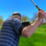 Rear view of a golfer at the top of the backswing with the Flyt Golf Swing Extender arm band visible on the trailing arm