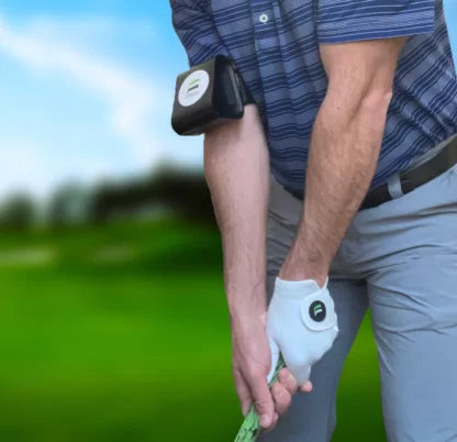A golfer wearing a swing extender device attached to his right arm, preparing to swing a golf club on a green field.
